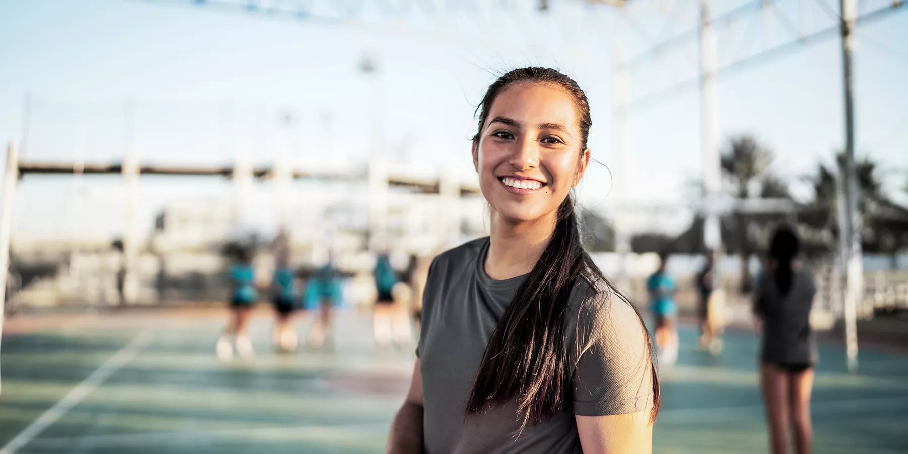 A young woman smiling during an active moment outdoors.