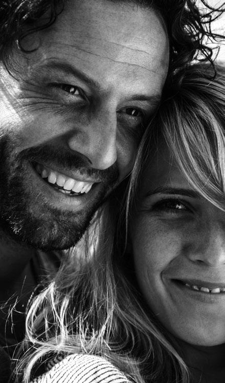 An adult couple sharing a close, smiling moment outdoors.